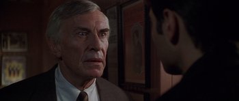 Movie still from “The X Files” (1998), directed by Rob Bowman – An older man wearing a suit and tie looking at a younger man; Close Up shot, Over the shoulder angle