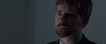 Movie still from “The X Files” (1998), directed by Rob Bowman – A person wearing a suit and a beard; Close Up shot, Over the shoulder angle