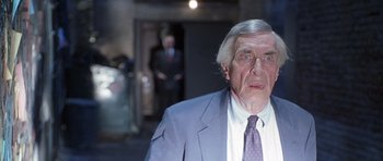 Movie still from “The X Files” (1998), directed by Rob Bowman – An older man wearing a suit and tie; Close Up shot, Over the shoulder angle