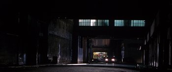 Movie still from “The X Files” (1998), directed by Rob Bowman – A car driving down a street at night; Extreme Wide shot, Low angle