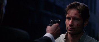 Movie still from “The X Files” (1998), directed by Rob Bowman – A person holding a gun in his hand; Close Up shot, Over the shoulder angle