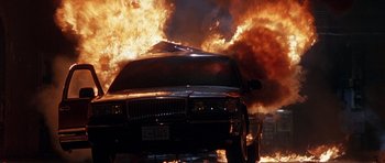 Movie still from “The X Files” (1998), directed by Rob Bowman – A car that is on fire in the street; Wide shot, Low angle