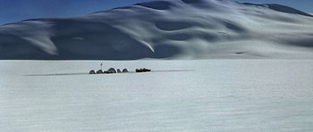 Movie still from “The X Files” (1998), directed by Rob Bowman – A dog sled traveling across a snow covered field; Extreme Wide shot, High angle
