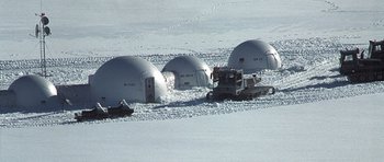 Movie still from “The X Files” (1998), directed by Rob Bowman – A group of people sitting on top of a snow covered ground; Extreme Wide shot, High angle