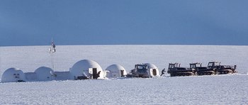 Movie still from “The X Files” (1998), directed by Rob Bowman – A group of vehicles in the middle of a snow covered field; Extreme Wide shot, High angle