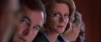 Movie still from “The X Files” (1998), directed by Rob Bowman – A person wearing glasses and a suit; Close Up shot, Over the shoulder angle