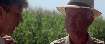 Movie still from “The X Files” (1998), directed by Rob Bowman – An older man wearing a straw hat in front of a corn field; Close Up shot, Low angle