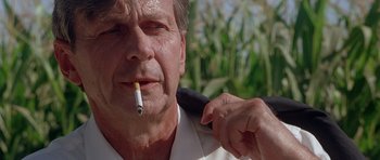 Movie still from “The X Files” (1998), directed by Rob Bowman – An older man is smoking a cigarette outside; Close Up shot, Low angle