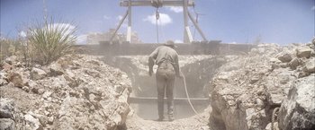 Movie still from “There Will Be Blood” (2007), directed by Paul Thomas Anderson – A man standing in the middle of an excavation area; Wide shot, Low angle