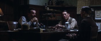 Movie still from “There Will Be Blood” (2007), directed by Paul Thomas Anderson – A group of men sitting at a table with food; Medium shot, Low angle