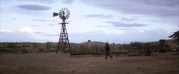 Movie still from “There Will Be Blood” (2007), directed by Paul Thomas Anderson – A person walking in a field near a windmill; Extreme Wide shot, Low angle