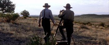 Movie still from “There Will Be Blood” (2007), directed by Paul Thomas Anderson – A couple of men standing next to each other in a field; Wide shot, Low angle