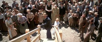 Movie still from “There Will Be Blood” (2007), directed by Paul Thomas Anderson – An old man holding a young girl in front of a crowd of people; Wide shot, High angle
