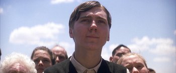 Movie still from “There Will Be Blood” (2007), directed by Paul Thomas Anderson – A young man in a suit and tie looking up at the sky; Close Up shot, Low angle