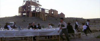Movie still from “There Will Be Blood” (2007), directed by Paul Thomas Anderson – A group of people sitting at a table with plates; Wide shot, Over the shoulder angle