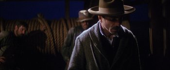 Movie still from “There Will Be Blood” (2007), directed by Paul Thomas Anderson – A man with a hat and a pipe in his mouth; Medium shot, Low angle