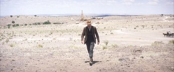 Movie still from “There Will Be Blood” (2007), directed by Paul Thomas Anderson – A man in a hat walking in the desert; Extreme Wide shot, Low angle