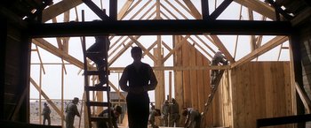 Movie still from “There Will Be Blood” (2007), directed by Paul Thomas Anderson – A woman standing in front of a wooden structure; Wide shot, Low angle