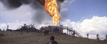 Movie still from “There Will Be Blood” (2007), directed by Paul Thomas Anderson – A man sitting in front of a burning building; Extreme Wide shot, Low angle