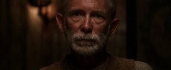 Movie still from “There Will Be Blood” (2007), directed by Paul Thomas Anderson – An older man with a beard and a mustache; Close Up shot, Over the shoulder angle