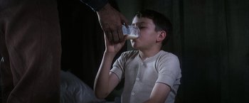 Movie still from “There Will Be Blood” (2007), directed by Paul Thomas Anderson – A man feeding a boy a glass of milk; Medium shot, High angle
