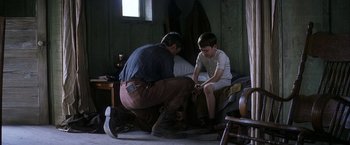 Movie still from “There Will Be Blood” (2007), directed by Paul Thomas Anderson – A man kneeling down next to a young boy; Medium shot, High angle