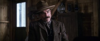 Movie still from “There Will Be Blood” (2007), directed by Paul Thomas Anderson – A man in a suit and a hat; Close Up shot, Over the shoulder angle