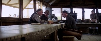 Movie still from “There Will Be Blood” (2007), directed by Paul Thomas Anderson – A group of men sitting around a table; Medium shot, Low angle