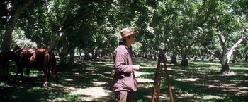 Movie still from “There Will Be Blood” (2007), directed by Paul Thomas Anderson – A man standing in the middle of a field with a camera; Wide shot, Over the shoulder angle