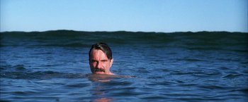 Movie still from “There Will Be Blood” (2007), directed by Paul Thomas Anderson – A man in the water with a mustache and beard; Medium shot, Low angle