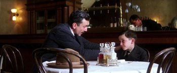 Movie still from “There Will Be Blood” (2007), directed by Paul Thomas Anderson – A man sitting at a table with a young boy; Medium shot, Over the shoulder angle