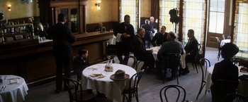 Movie still from “There Will Be Blood” (2007), directed by Paul Thomas Anderson – A group of people sitting at a table in a restaurant; Wide shot, High angle