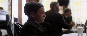 Movie still from “There Will Be Blood” (2007), directed by Paul Thomas Anderson – A young boy wearing a suit and tie looking to his left; Close Up shot, Over the shoulder angle