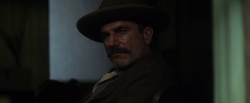 Movie still from “There Will Be Blood” (2007), directed by Paul Thomas Anderson – A person wearing a suit and hat; Close Up shot, Low angle