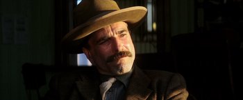 Movie still from “There Will Be Blood” (2007), directed by Paul Thomas Anderson – A man with a mustache wearing a suit and a hat; Close Up shot, Low angle