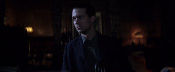 Movie still from “There Will Be Blood” (2007), directed by Paul Thomas Anderson – A man in a suit and tie in a dark room; Close Up shot, Low angle