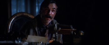 Movie still from “There Will Be Blood” (2007), directed by Paul Thomas Anderson – A man sitting at a table in a dimly - lit room; Close Up shot, Low angle