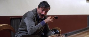 Movie still from “There Will Be Blood” (2007), directed by Paul Thomas Anderson – A man sitting on the ground eating a piece of cake; Close Up shot, Low angle