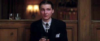 Movie still from “There Will Be Blood” (2007), directed by Paul Thomas Anderson – A man in a suit and tie holding a drink; Close Up shot, High angle