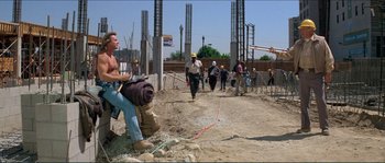 Movie still from “They Live” (1988), directed by John Carpenter – A group of construction workers walking down a dirt road; Wide shot, Over the shoulder angle