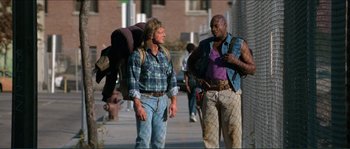 Movie still from “They Live” (1988), directed by John Carpenter – Two men walking down the street talking to each other; Wide shot, Low angle