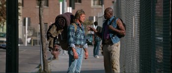Movie still from “They Live” (1988), directed by John Carpenter – A man and a woman talking on the sidewalk; Wide shot, Over the shoulder angle