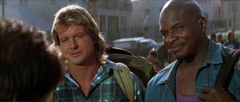 Movie still from “They Live” (1988), directed by John Carpenter – Two men standing next to each other on the street; Close Up shot, Low angle