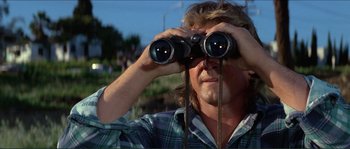 Movie still from “They Live” (1988), directed by John Carpenter – A man looking through a pair of binoculars; Close Up shot, Low angle