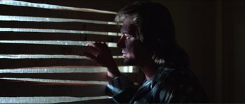 Movie still from “They Live” (1988), directed by John Carpenter – A man sitting in front of a window blinds; Close Up shot, Low angle