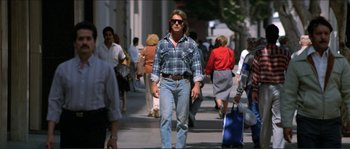 Movie still from “They Live” (1988), directed by John Carpenter – A man walking down the street with a blue bag; Wide shot, Low angle