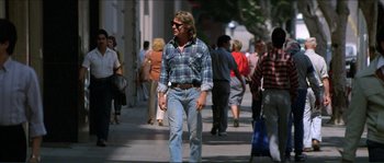 Movie still from “They Live” (1988), directed by John Carpenter – A man walking down a sidewalk with a crowd of people; Wide shot, Low angle