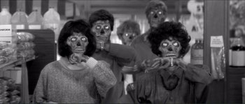 Movie still from “They Live” (1988), directed by John Carpenter – A black and white photo of a group of zombies; Medium shot, Low angle