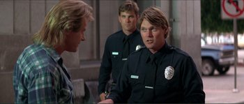 Movie still from “They Live” (1988), directed by John Carpenter – Two police officers talking to a man in uniform; Medium shot, Over the shoulder angle