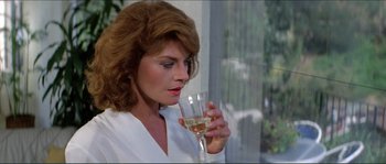 Movie still from “They Live” (1988), directed by John Carpenter – A woman holding a glass of wine in her hand; Close Up shot, Over the shoulder angle